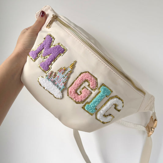 Beige pouch with colorful text and castle design held by a hand against a white background