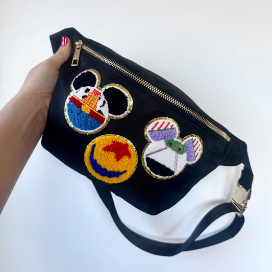 Black pouch with colorful embroidered designs held by a hand on a white background