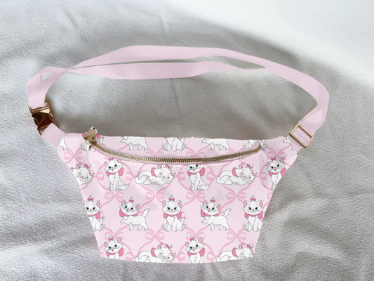 Pink fanny pack with kitten and bow pattern on a grey surface